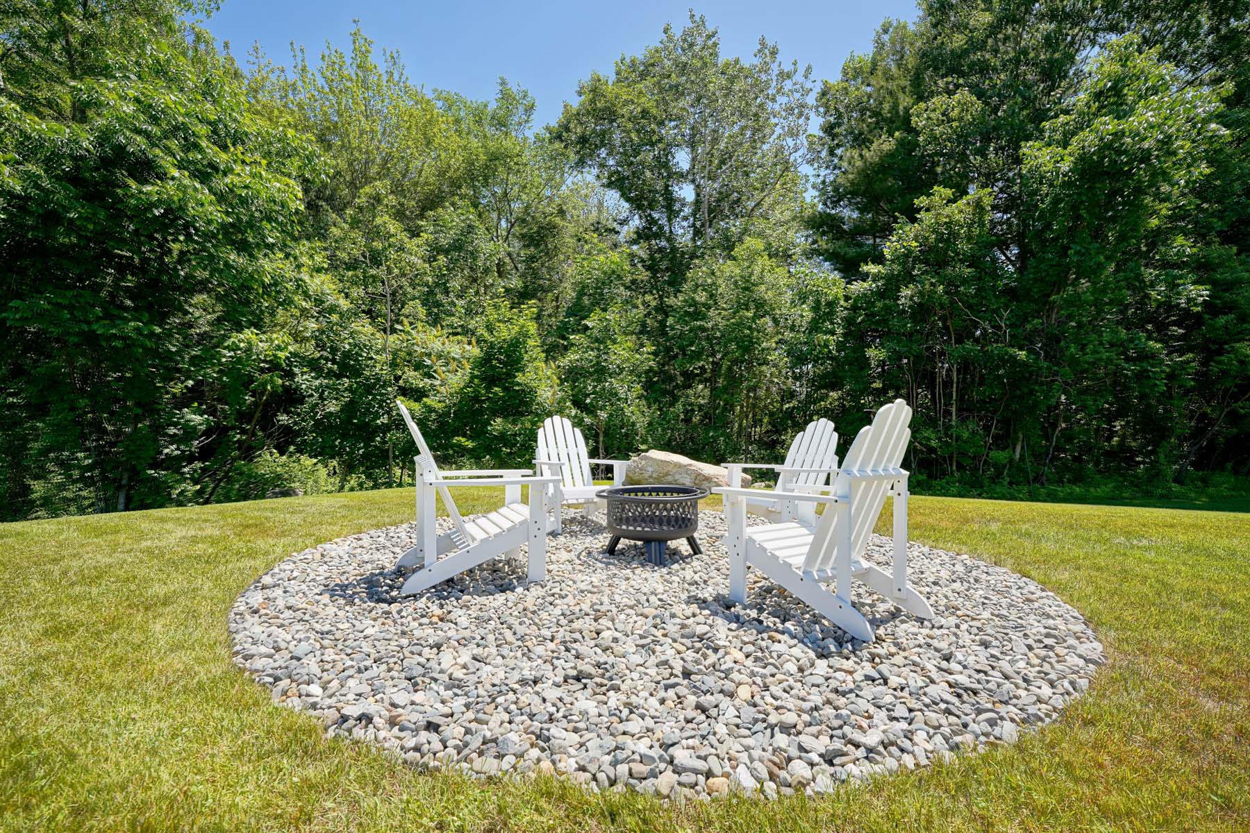 seating area surrounding a fire pit with grass and trees